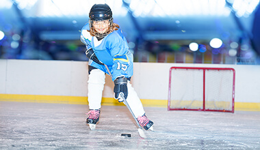 Happy girl passing the puck during hockey game